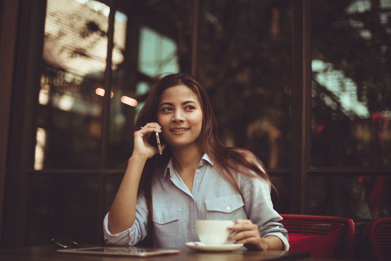 Business Professional Taking a Call in a Café Business lady talking on the phone while sitting in a café, balancing work and a relaxed environment.